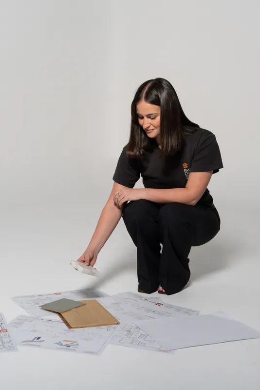 Sydney Drafting designer crouching over architectural plans laid on the floor