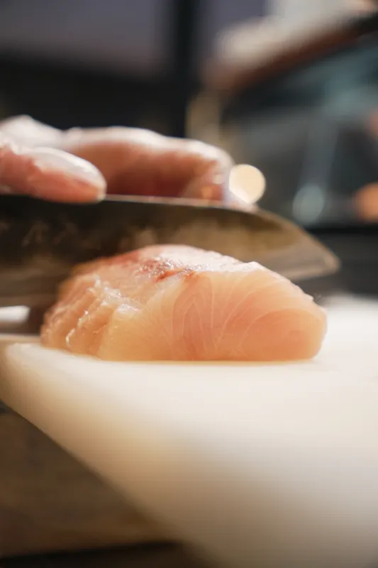 Chef slicing raw kingfish for sashimi at Aji Japanese Cuisine