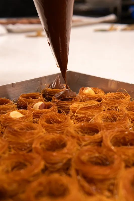 Piping cream into rows of pastry nests at Galerie Pâtisserie