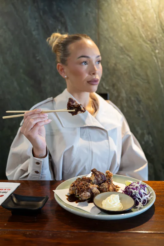 Diner lifting a piece of meat with chopsticks over a plate of Lebanese dishes at Gebran