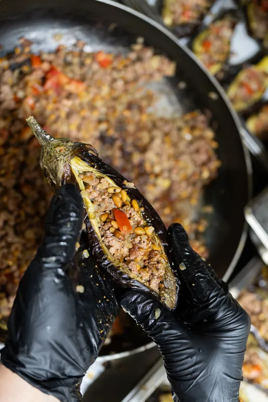 Close-up of a stuffed eggplant held in gloved hands at Massaya