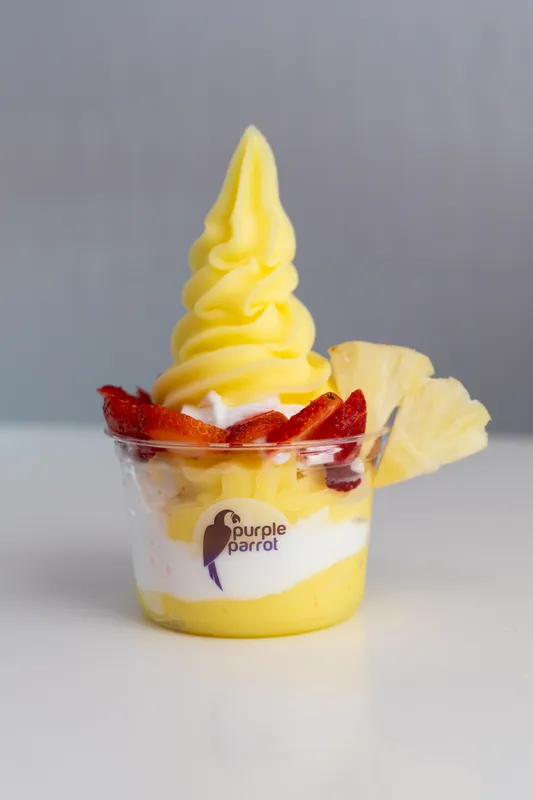 Purple Parrot pineapple soft serve topped with strawberries and pineapple
