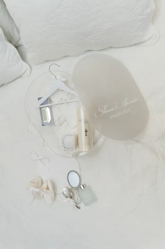 Christening set on white linen: a monogrammed acrylic plaque, a candle and small gifts