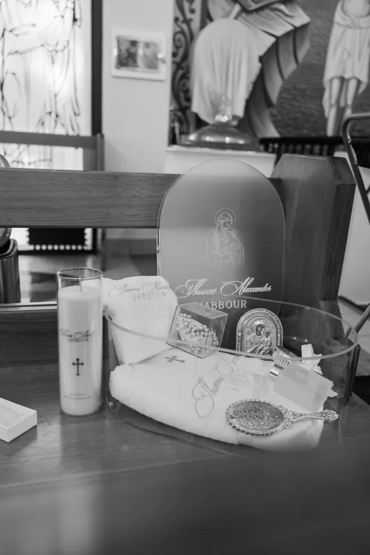 Black-and-white photo of a christening box with a candle, oil bottle and baptism towel on a table