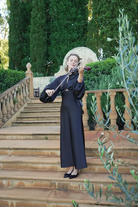 Violinist in a long black dress playing on garden stairs before a proposal