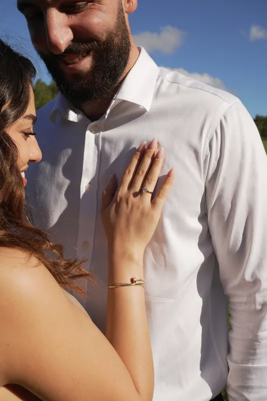 Close-up of a new fiancée’s hand with her engagement ring resting on her partner’s shirt
