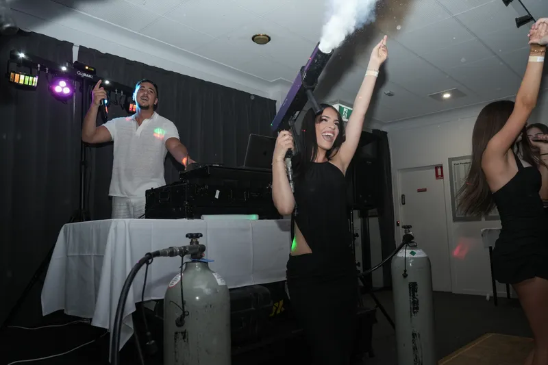 Guests dancing as CO2 jets fire over the DJ booth at a party