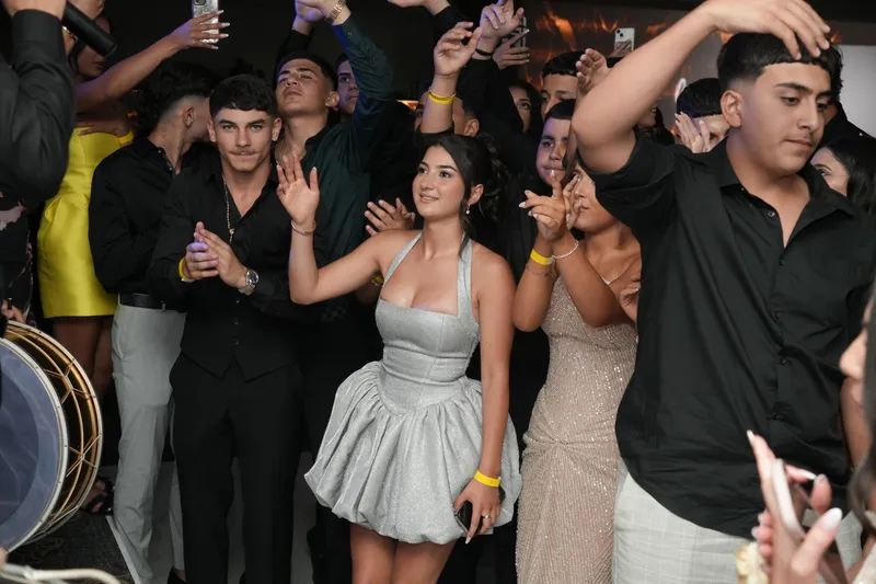 Crowd of young guests cheering and dancing at a party