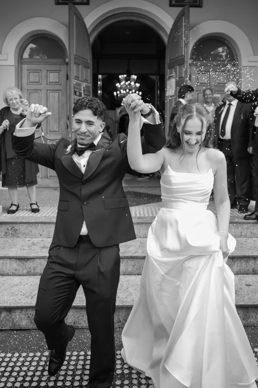 Black-and-white photo of the newlyweds dancing down the church steps