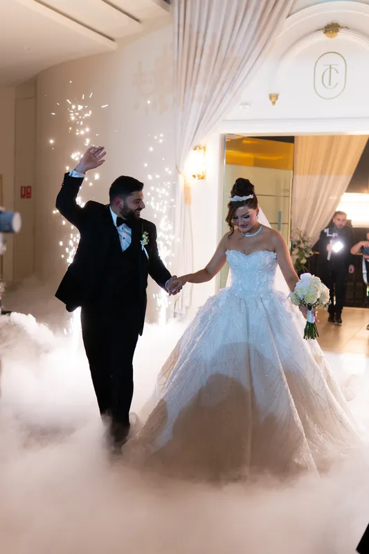 Bride and groom making their grand entrance through a cloud of low fog with cold-spark fountains
