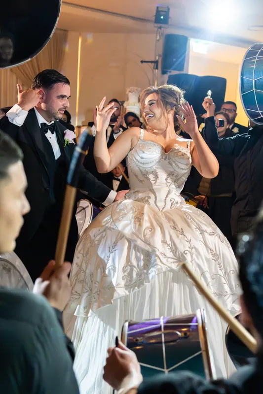 Bride dancing with guests in a pearl ball gown at her wedding reception