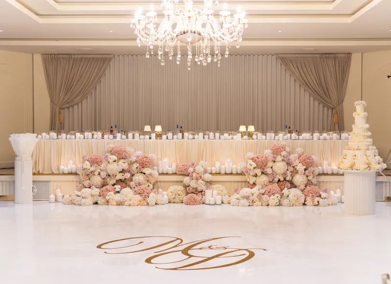 Bridal table with a floral garland and a monogram projected on the dance floor