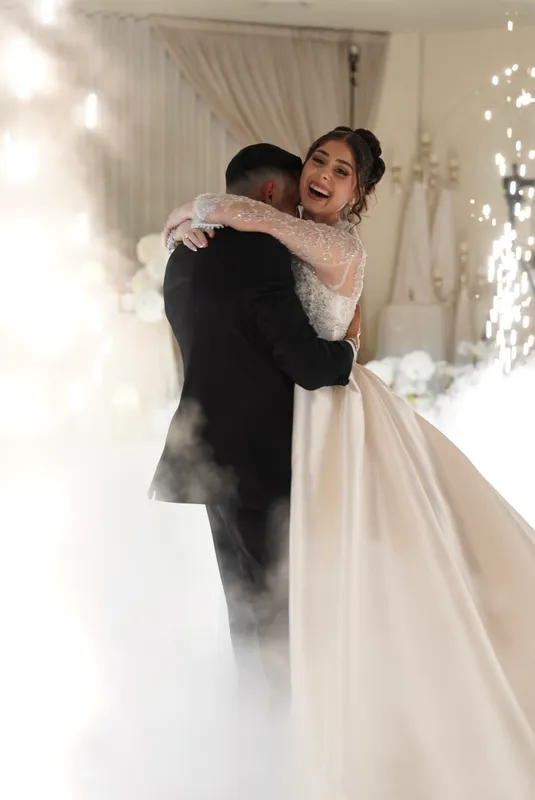 Bride and groom embracing in a cloud of white fog during their first dance